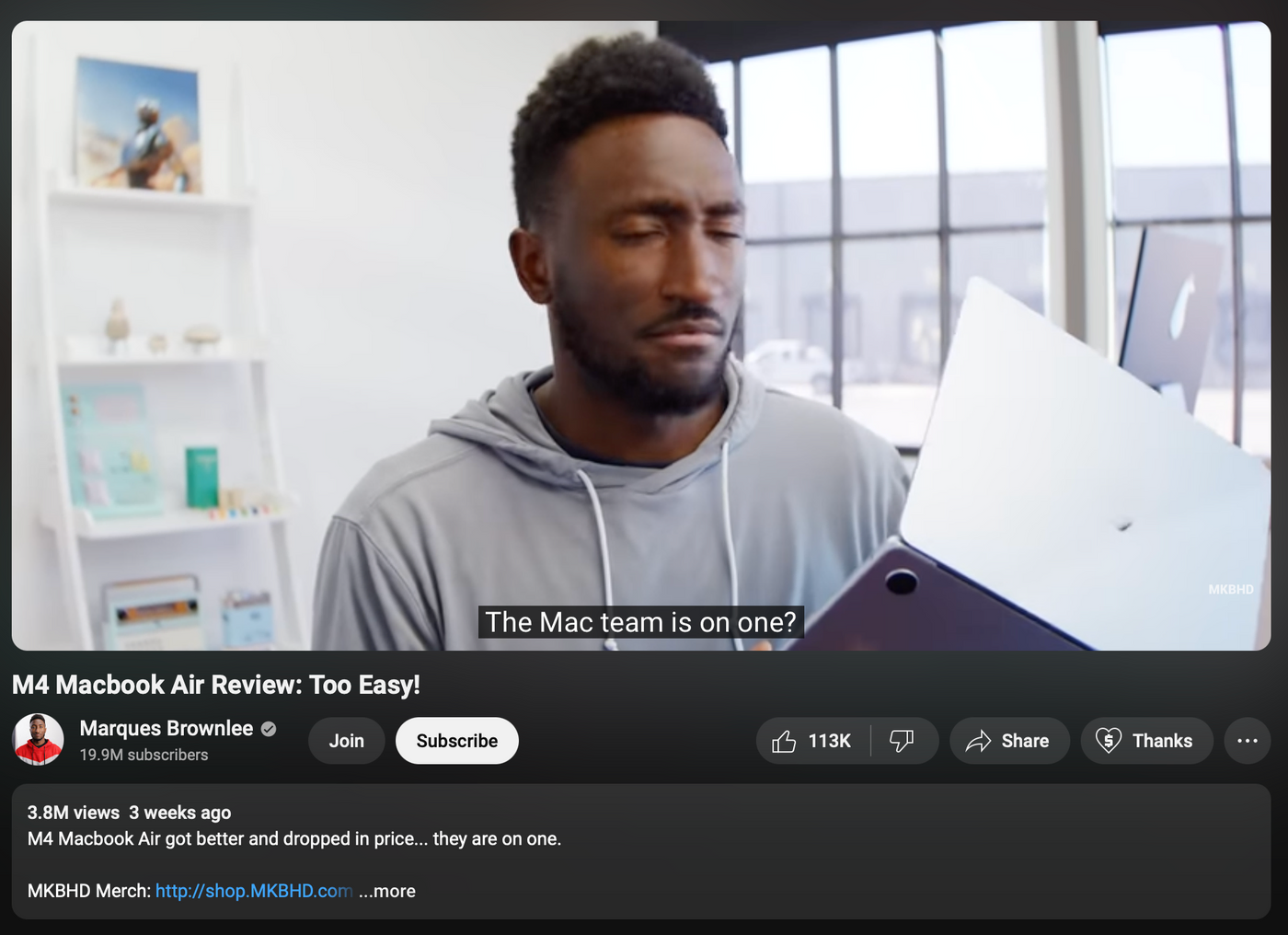 Man reviews MacBook Air in bright room, looking puzzled. Text: "The Mac team is on one?" Shelves and window in background.