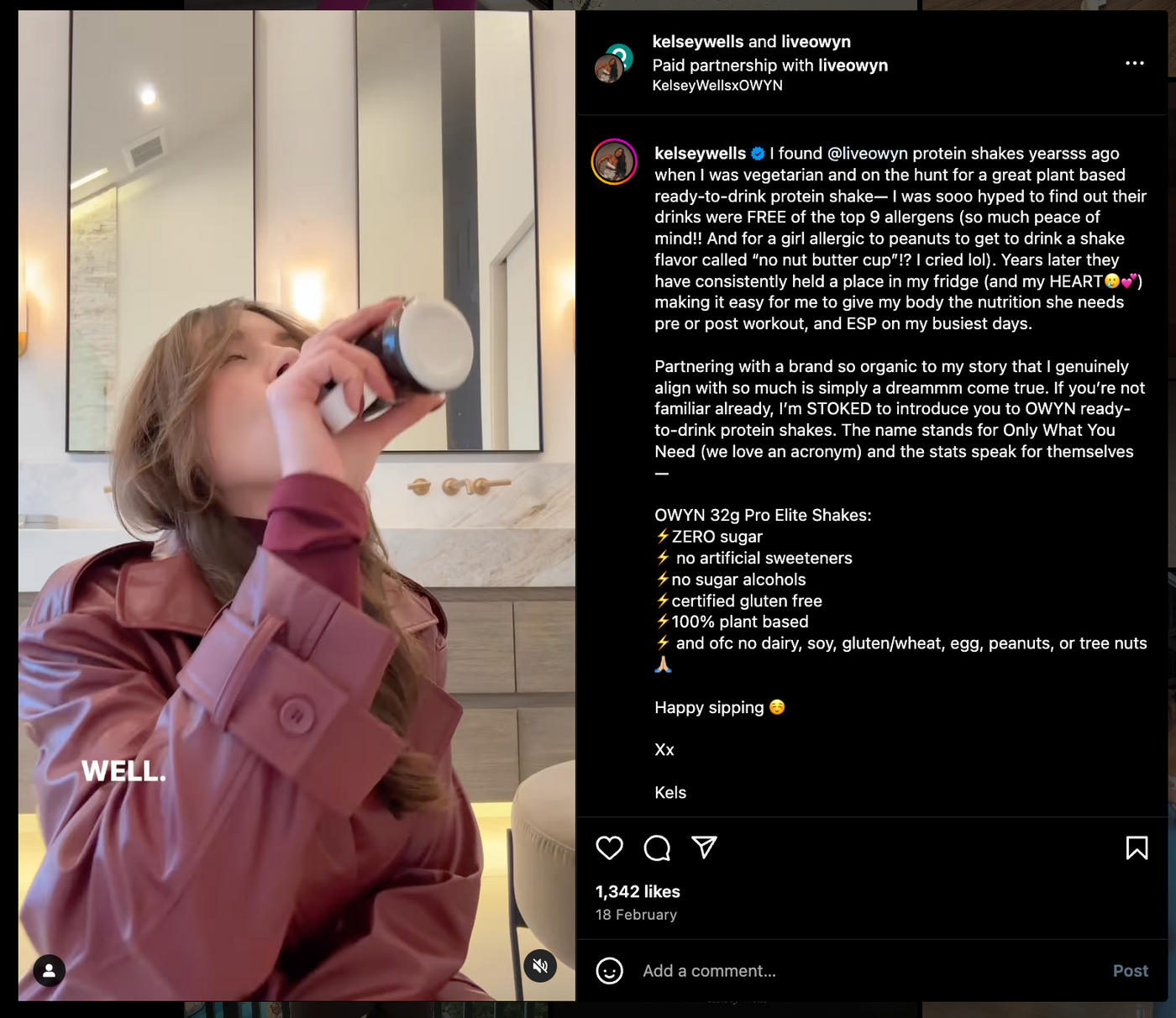 Person in a maroon jacket drinks from a bottle in a stylish bathroom with framed mirrors and warm lighting. "WELL" text on the image.