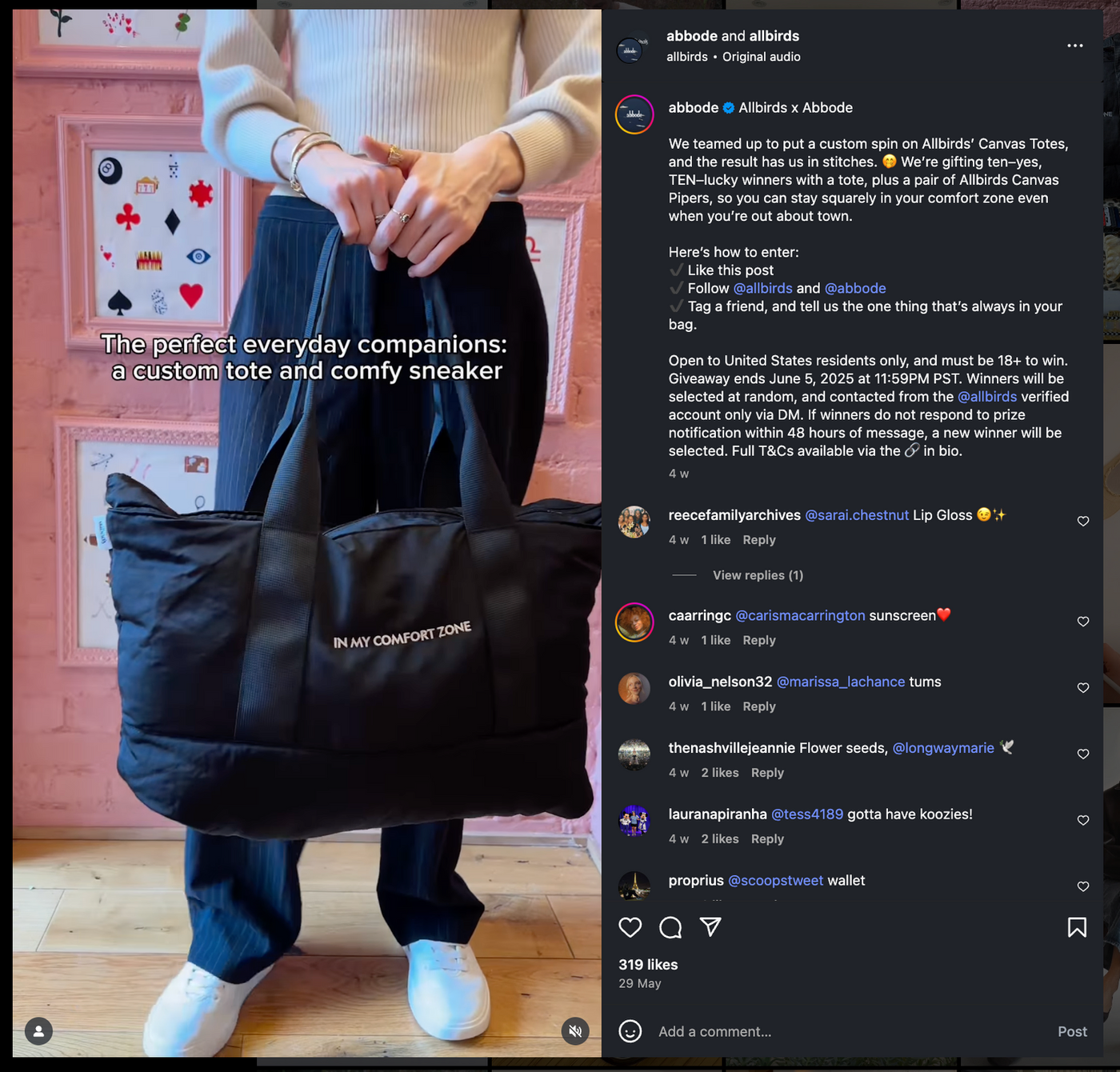 Person in a white sweater holds a black tote bag with "IN MY COMFORT ZONE" text. Pink wall with framed cards in the background.