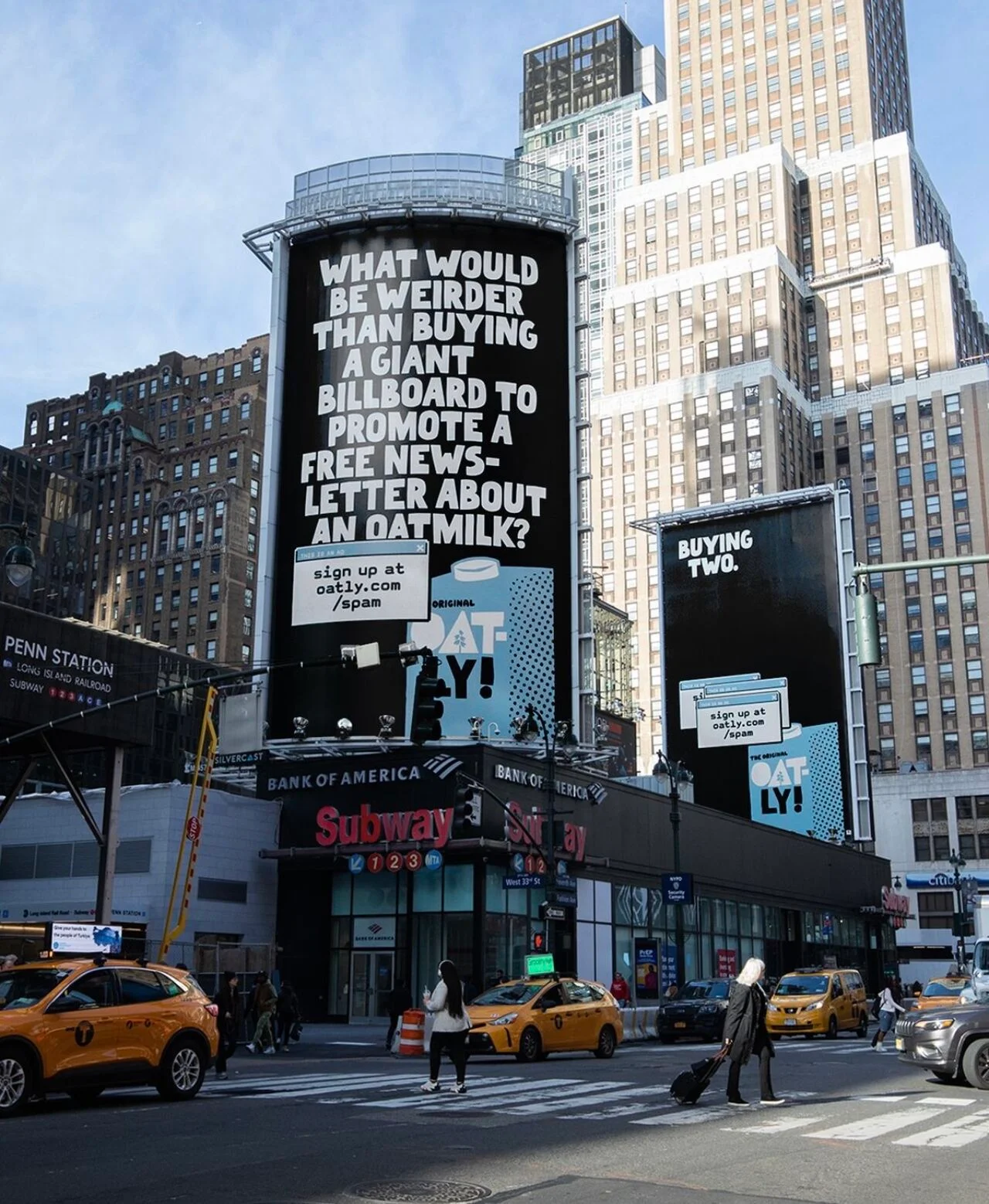 Large black billboards in a city advertise oat milk with witty text. Yellow taxis and people in coats cross the street below.