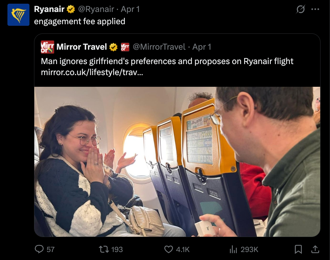 Man proposing on a Ryanair flight, woman smiling and surprised. Bright cabin interior, yellow seat backs. Text: "engagement fee applied."